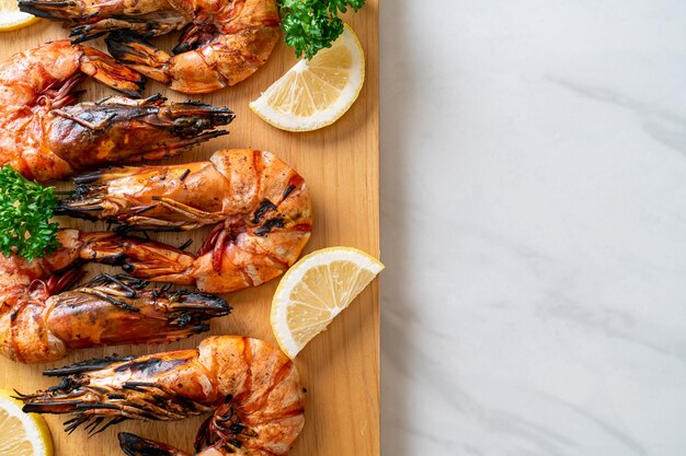 Langostinos a la plancha o gambas con limón sobre tablero de madera