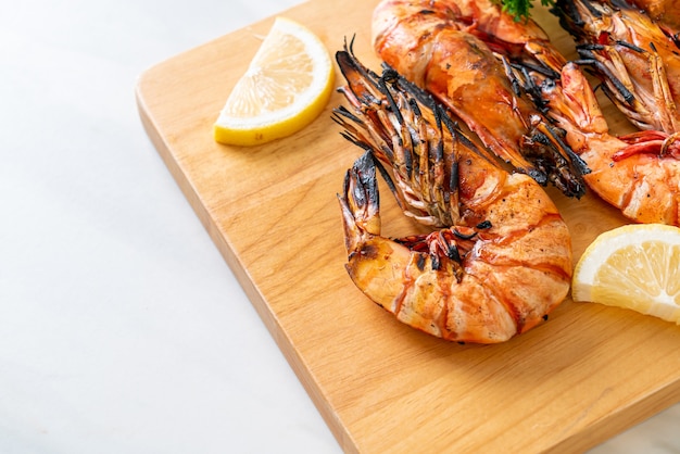 Langostinos a la plancha o gambas con limón sobre tablero de madera