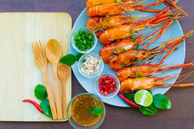 Langostinos a la plancha con salsa de marisco sobre la mesa de maderaLangostinos o gambas a la plancha con perejil o