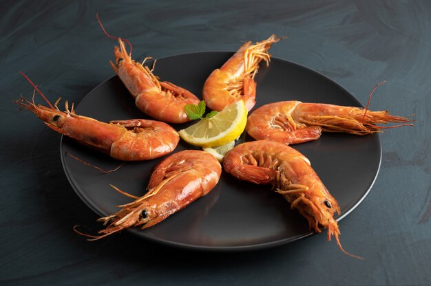 Langostinos a la plancha sobre un plato negro, sobre una rústica mesa de madera