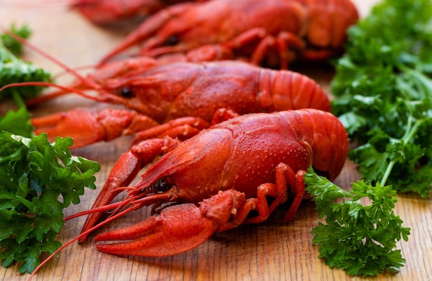 Langostinos rojos hervidos o cangrejos con perejil en un menú de primer plano de tablero de cocina de madera para un pub