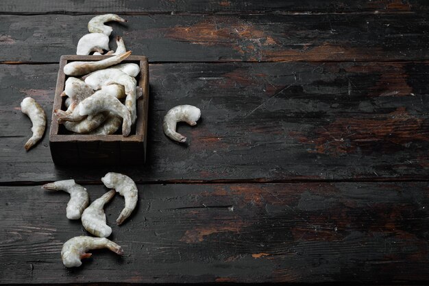 Langostinos tigre crudos crudos congelados, camarones, en la vieja mesa de madera oscura, con espacio para copiar texto