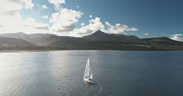 Foto langsam fahrende segelyacht an der berg-ozean-küste segelboot-regatta-rennen in der see-bucht luft-sonne