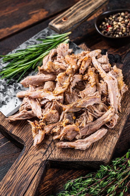 Langsam gekochtes Schweinefleisch auf einem Holzbrett mit Metzgerbeil. Dunkles Holz