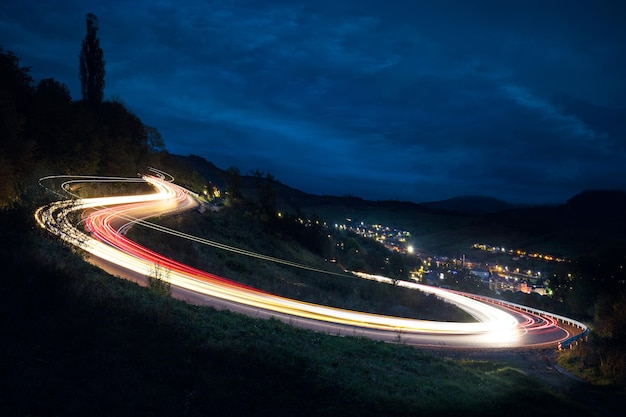 Langzeitbelichtung Autolichter auf dem Asphalt nachts auf einer beleuchteten Bergstraße