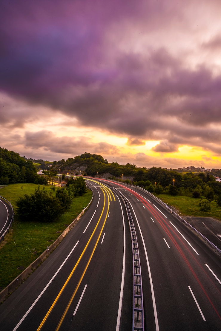Foto langzeitbelichtung bei sonnenuntergang auf einer straße, treten sie in die wolken ein, um die sonne zu bedecken, und nehmen sie eine orange farbe an. vertikales foto, baskenland