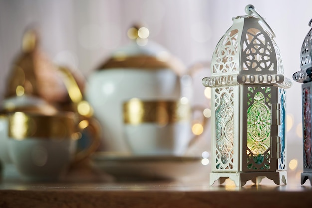 Lanterna árabe ornamental com vela acesa brilhando e belo conjunto de chá como pano de fundo