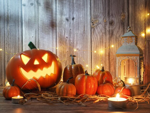 Lanterna de cabeça de abóbora de Halloween com velas e uma abóbora em fundo de madeira