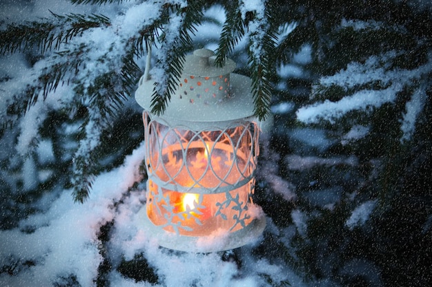 Lanterna de Natal com vela acesa em fundo de neve de inverno.