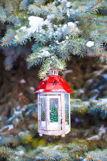 Lanterna de Natal decorativa no ramo de abeto na neve, dia de inverno