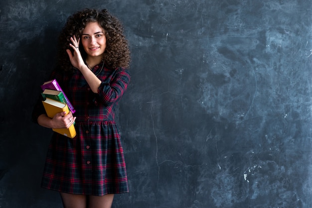 Lanzamiento del estudio de una muchacha morena rizada sonriente con un libro en sus manos