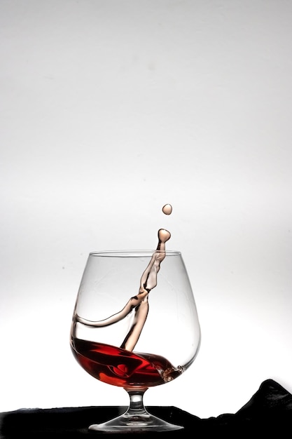 Lanzamiento vertical de vaso de licor con vino salpicado en el interior