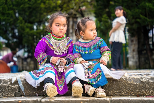 Lao Cai VIETNAM MAR 12 2023 hermoso retrato de una niña vietnamita HMong minoría étnica saluda a los turistas sentados frente a la Iglesia y vende artículos hechos a mano en el centro de Sapa