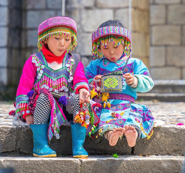 Lao Cai VIETNAM MAR 12 2023 hermoso retrato de una niña vietnamita HMong minoría étnica saluda a los turistas sentados frente a la Iglesia y vende artículos hechos a mano en el centro de Sapa