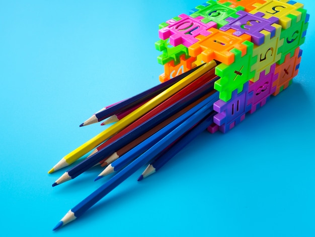 Los lápices de colores en colorfull del sostenedor del lápiz hacen el número del rompecabezas de la forma en fondo azul