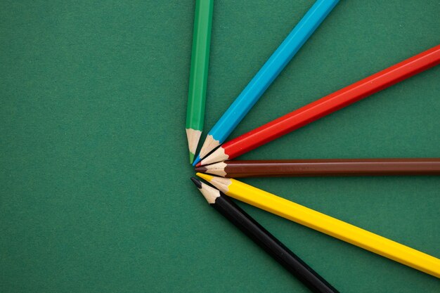 Lápices de colores con diferente color sobre fondo verde