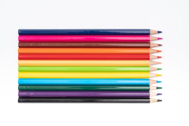 Lápices de colores en una fila aislado sobre fondo blanco.