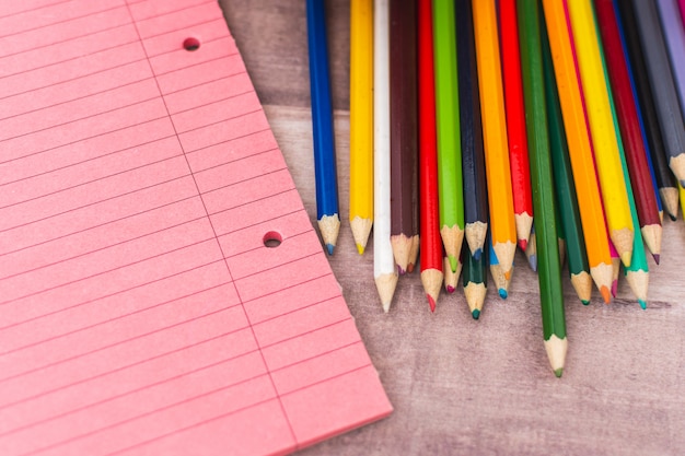 Lápices de colores junto a cuadernos sobre un escritorio