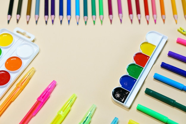 Lápices de colores y marcadores con bolígrafos y pintura de fondo de papel con espacio de copia creati para niños