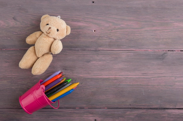 Foto lápices de colores y oso de juguete en la mesa de madera concepto de educación de la escuela primaria