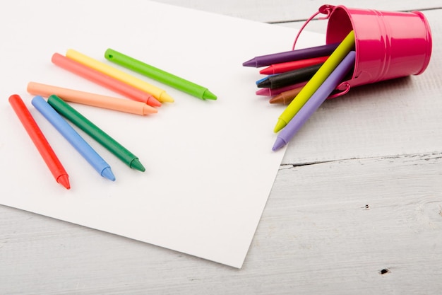 Lápices de colores y papel en blanco en el escritorio.