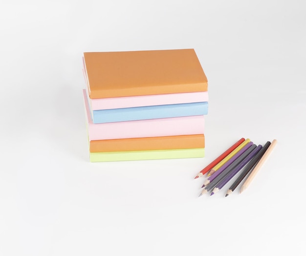 Lápices de colores y pila de libros sobre fondo blanco foto wi