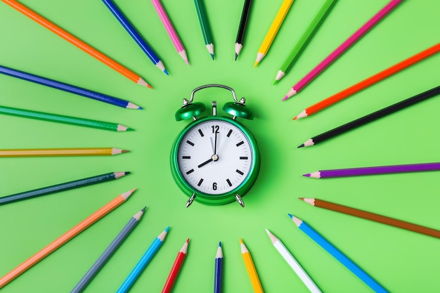 Lápices de colores y reloj despertador Concepto de regreso a la escuela