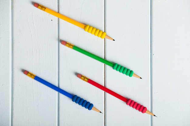 Lápices de colores sobre mesa de madera blanca