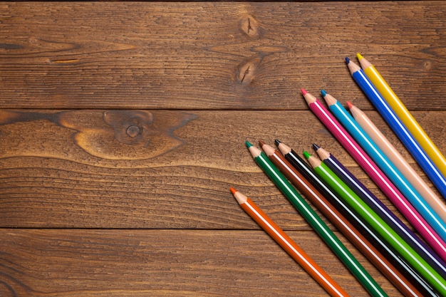 Lápices de colores sobre tabla de madera, vista superior