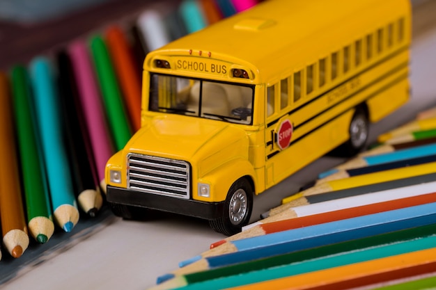 Lápices de colores sobre útiles escolares de autobuses escolares amarillos