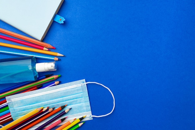 Lápices de colores y vista superior de la mascarilla médica. Concepto de educación pandémica