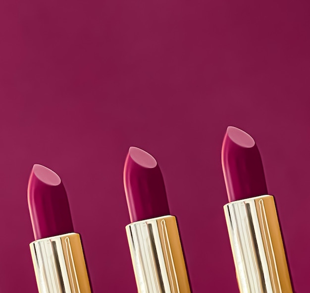 Lápices labiales morados en tubos dorados sobre fondo de color maquillaje de lujo y cosméticos para el diseño de productos de marca de belleza