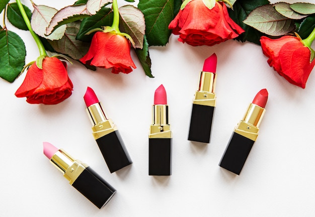 Lápices labiales y rosas rojas