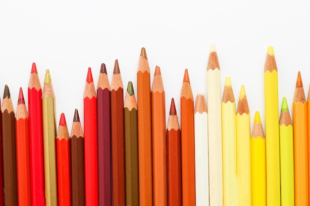 Lápices multicolores yacen sobre una mesa blanca la gama roja de colores