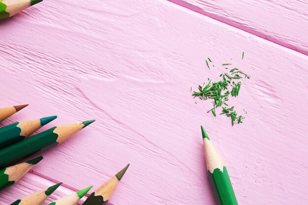 Lápices verdes afilados sobre fondo rosa