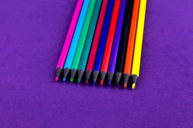 Lápis coloridos de escritório escolar isolados em roxo