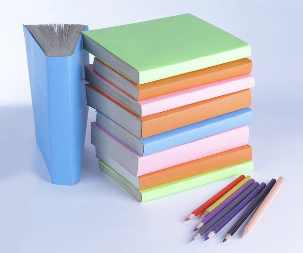 Lápis coloridos e pilha de livros sobre fundo branco foto wi