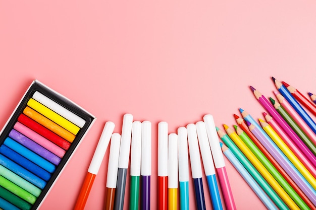 Lápis coloridos pastéis canetas de feltro em um conceito de fundo rosa para um hobby ou escola de desenho para crianças espaço de cópia plana