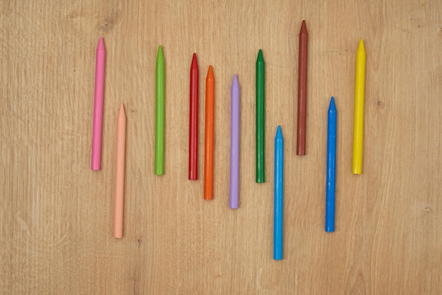 Lápis de cera multicoloridos infantis para desenhar em uma mesa de madeira.