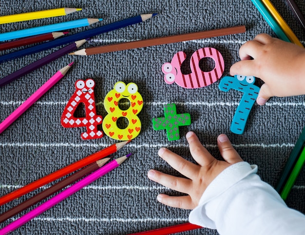 Lápis de cor coloridos e figura com mãos de criança pequena. Plano de fundo pré-escolar e do jardim de infância. De volta ao conceito de escola.