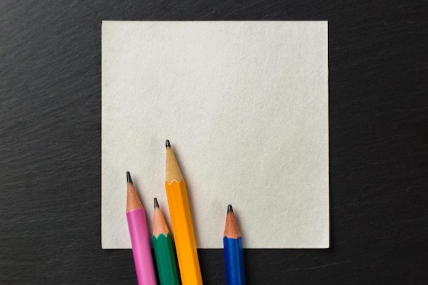 Lápis de cor em papel para anotações em um fundo cinza. Copie o espaço.