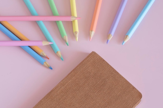 Lápis de cor pastel vista superior na educação do conceito de ilustração de fundo rosa e de volta à escola