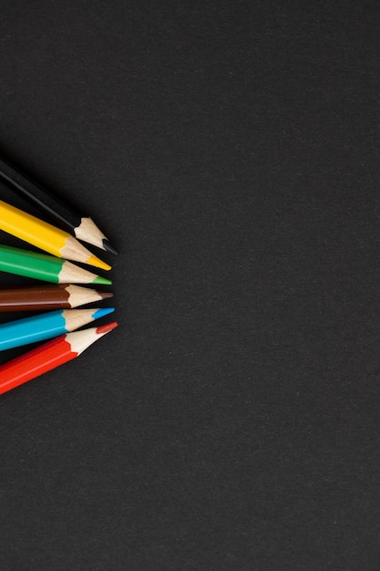Lápis de cor sobre fundo preto de volta ao conceito de escola