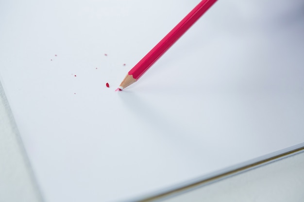 Lápis de cor vermelha com ponta quebrada com caderno