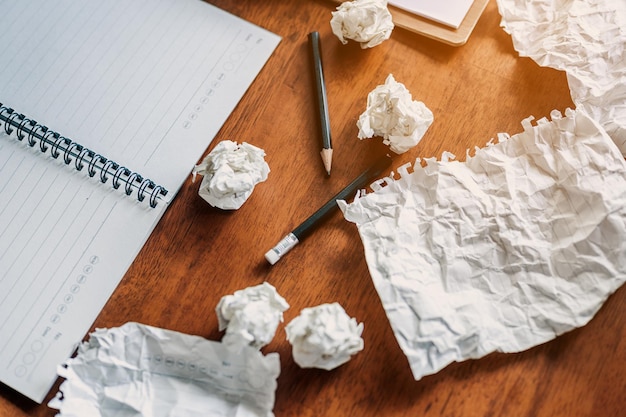 Lápis de quebra de modo irritado e papel amassado na mesa sem ideia, conceito, sem ideia caderno vazio na mesa de madeira com papéis amassados ao redor