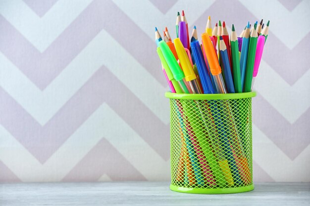 Lápis em suporte metálico sobre fundo colorido
