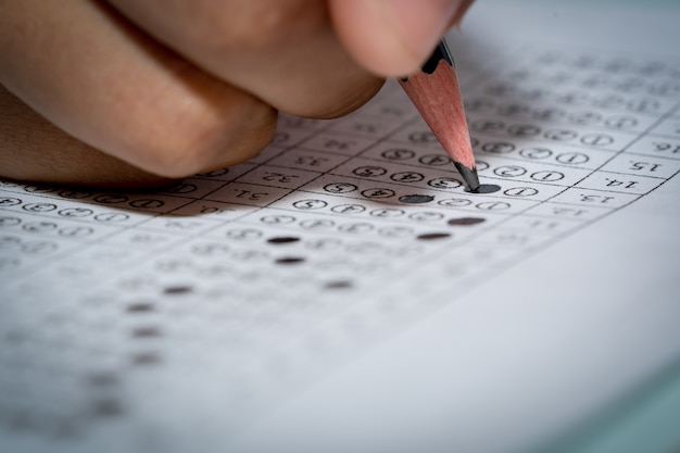 Lápis na mão segurando para escrever o teste de resposta da pergunta em papel de escolha múltipla