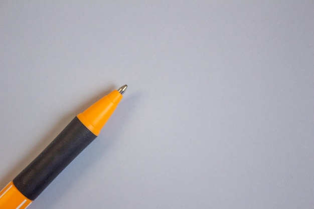 Un lápiz amarillo con una punta negra se asienta sobre un fondo gris.