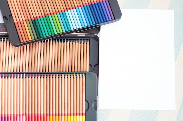Lápiz de colores en caja en piso con papel blanco