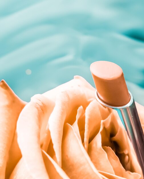 Lápiz labial amarillo y flor de rosa sobre fondo líquido maquillaje de glamour a prueba de agua y producto cosmético de brillo de labios para diseño de vacaciones de marca de belleza de lujo